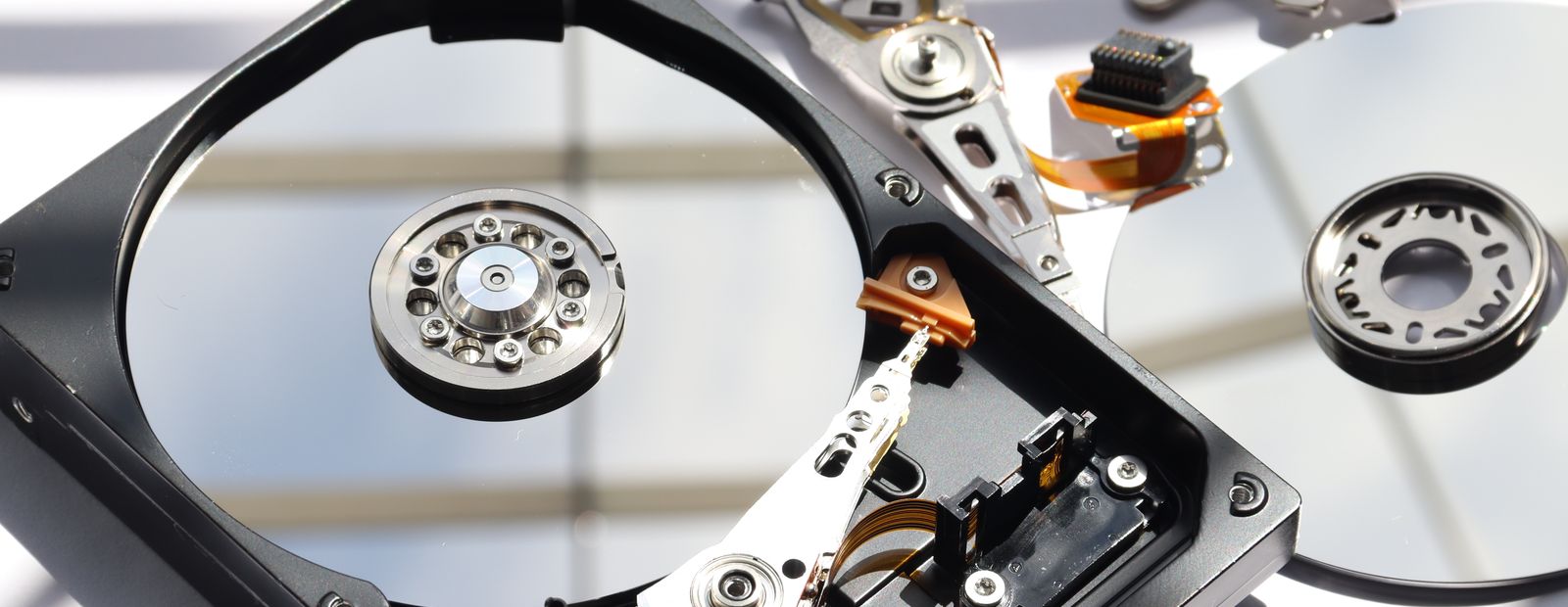 The inside of an opened hard drive, showing the platter and the head assembly that reads it